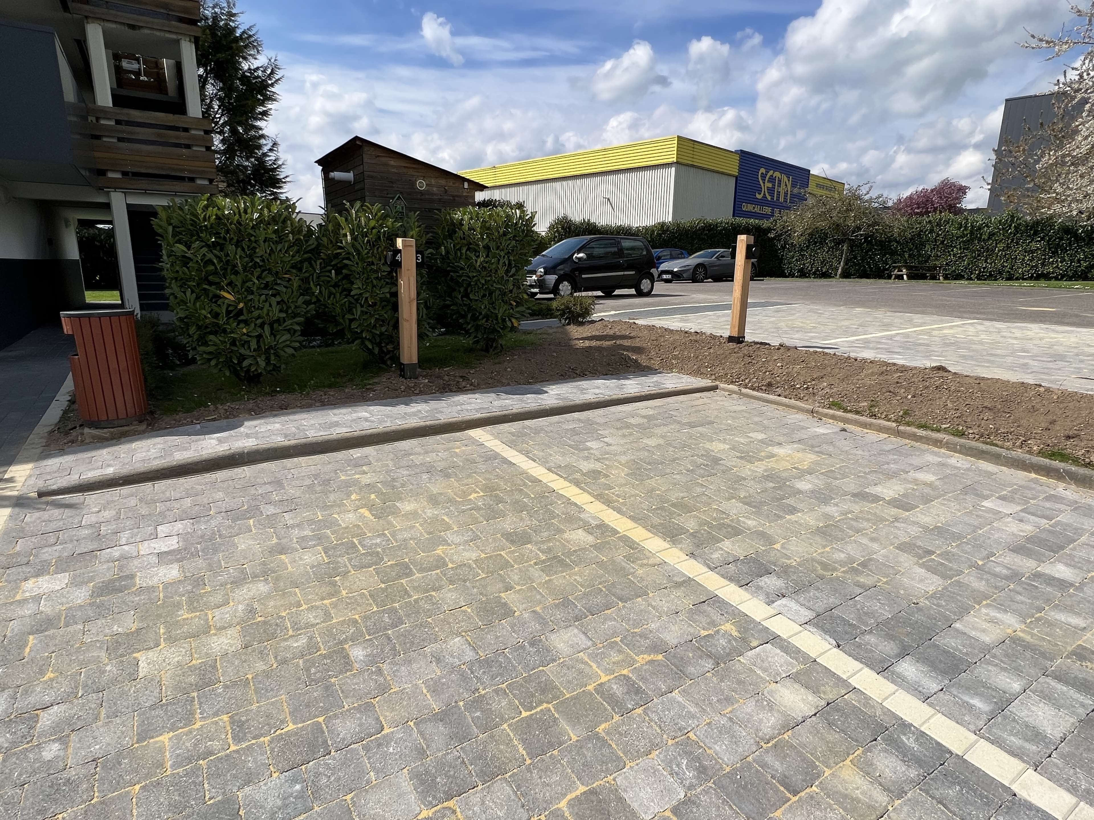 Un área de estacionamiento con superficie pavimentada y un edificio con techo amarillo al fondo.