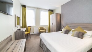 A hotel room with a large bed, a desk, a chair, and a TV. - Phoenix Hotel (London)
