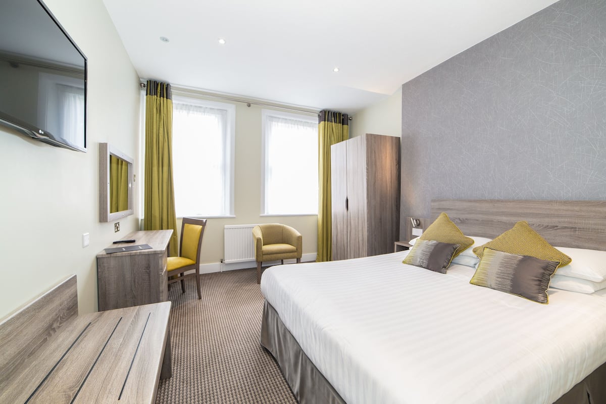 Une chambre d’hôtel avec un grand lit, un bureau, une chaise et un téléviseur.