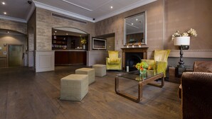 A spacious living room with a fireplace, comfortable seating, a television, and a bookshelf. - Phoenix Hotel (London)