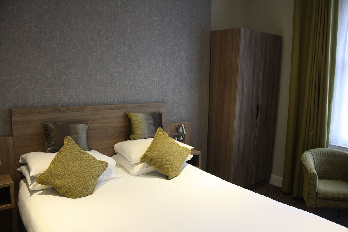 Une chambre d’hôtel avec un grand lit, deux tables de chevet, une armoire et une chaise.
