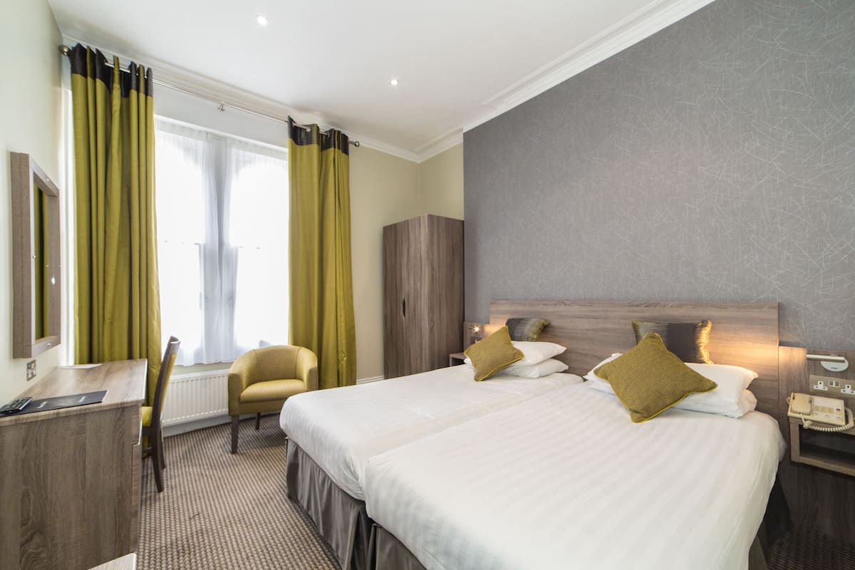 Une chambre d’hôtel avec un grand lit, un bureau, une chaise et une armoire.