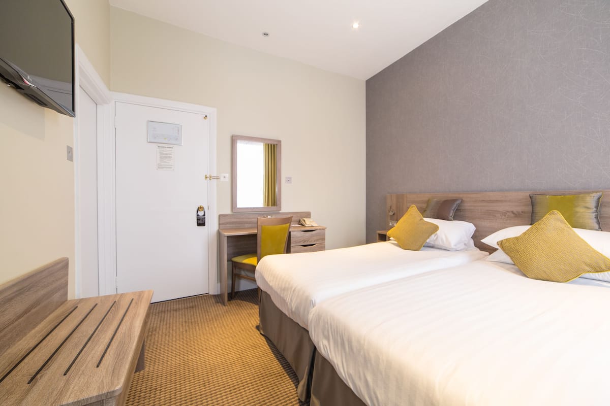 Une chambre d’hôtel avec un lit, un bureau, une chaise, une télévision et une porte.