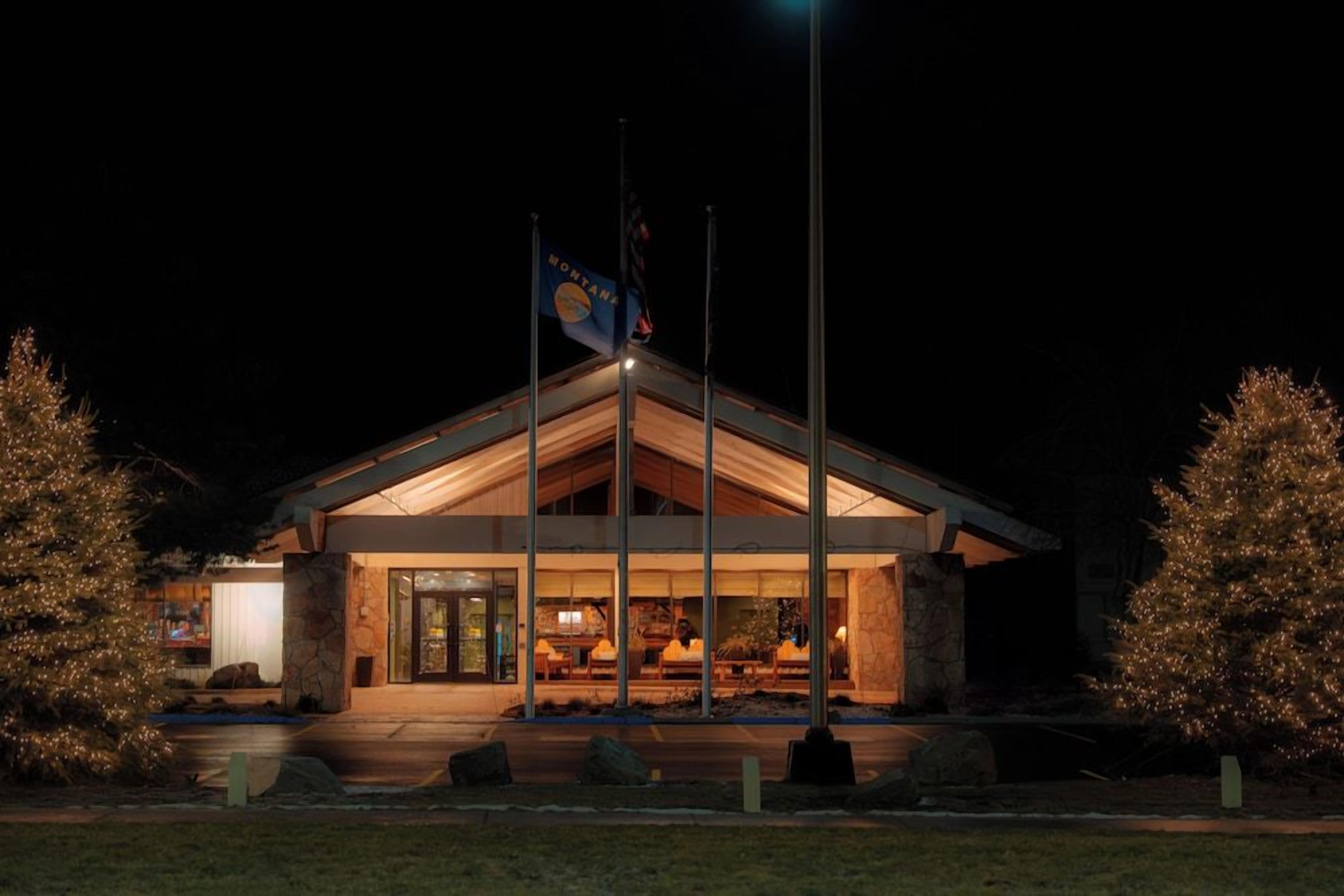 A building with a stone facade, a flagpole with a flag, and a well-lit entrance.