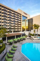 Un hotel con piscina, mobiliario exterior y un edificio grande con balcones.