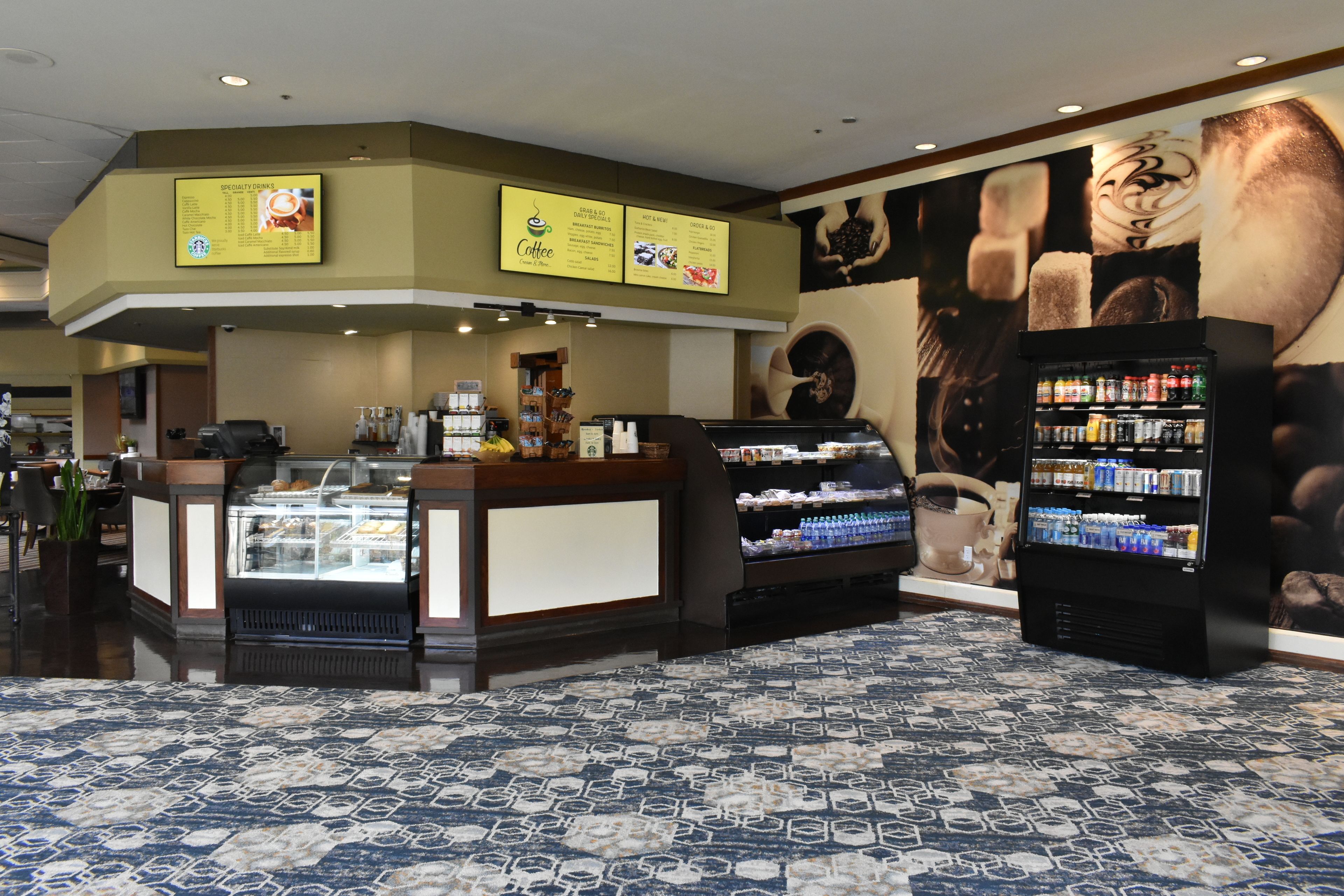 A coffee shop with a counter, display cases, and a beverage dispenser.