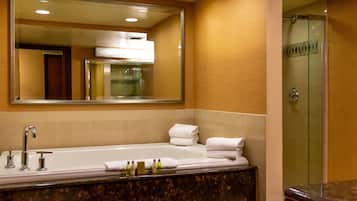 Une salle de bain dotée d’un grand miroir, d’une baignoire, d’une douche et d’un comptoir en marbre.