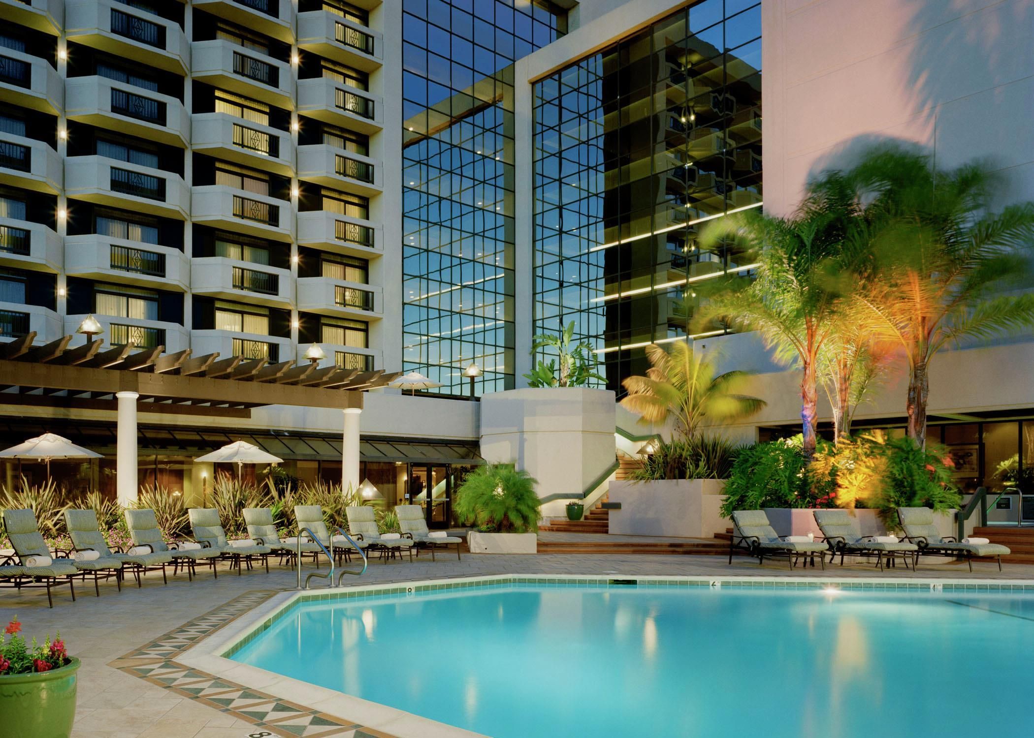 Um hotel com piscina, espreguiçadeiras e um edifício moderno com varandas.