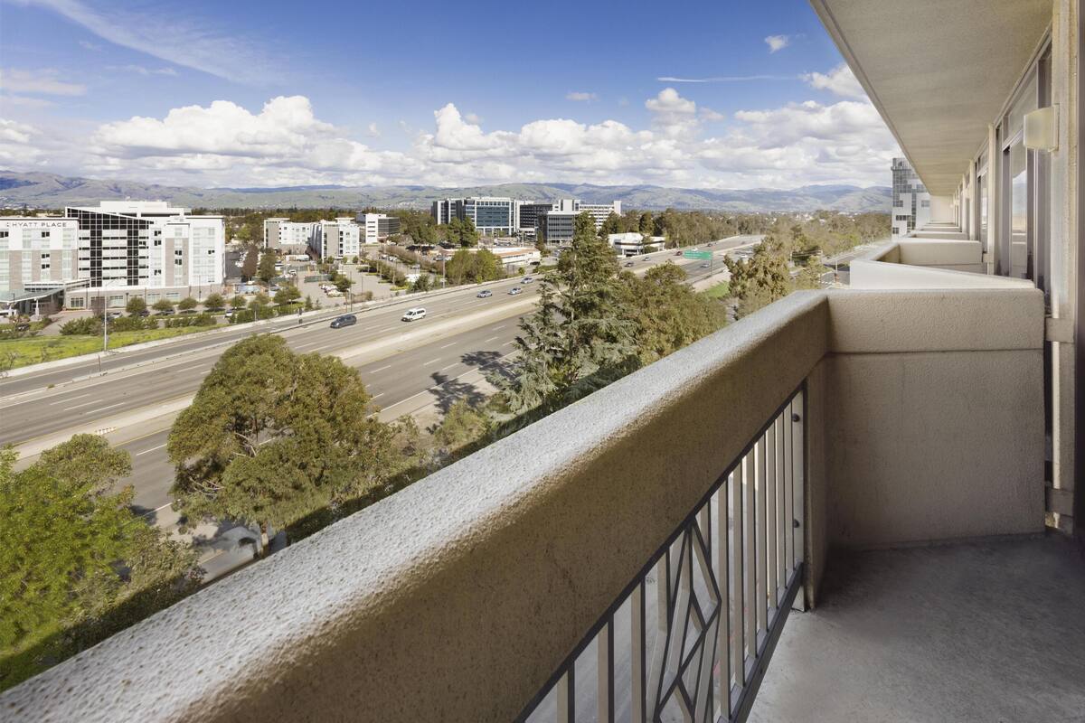 A hotel with a balcony overlooking a highway and distant mountains.