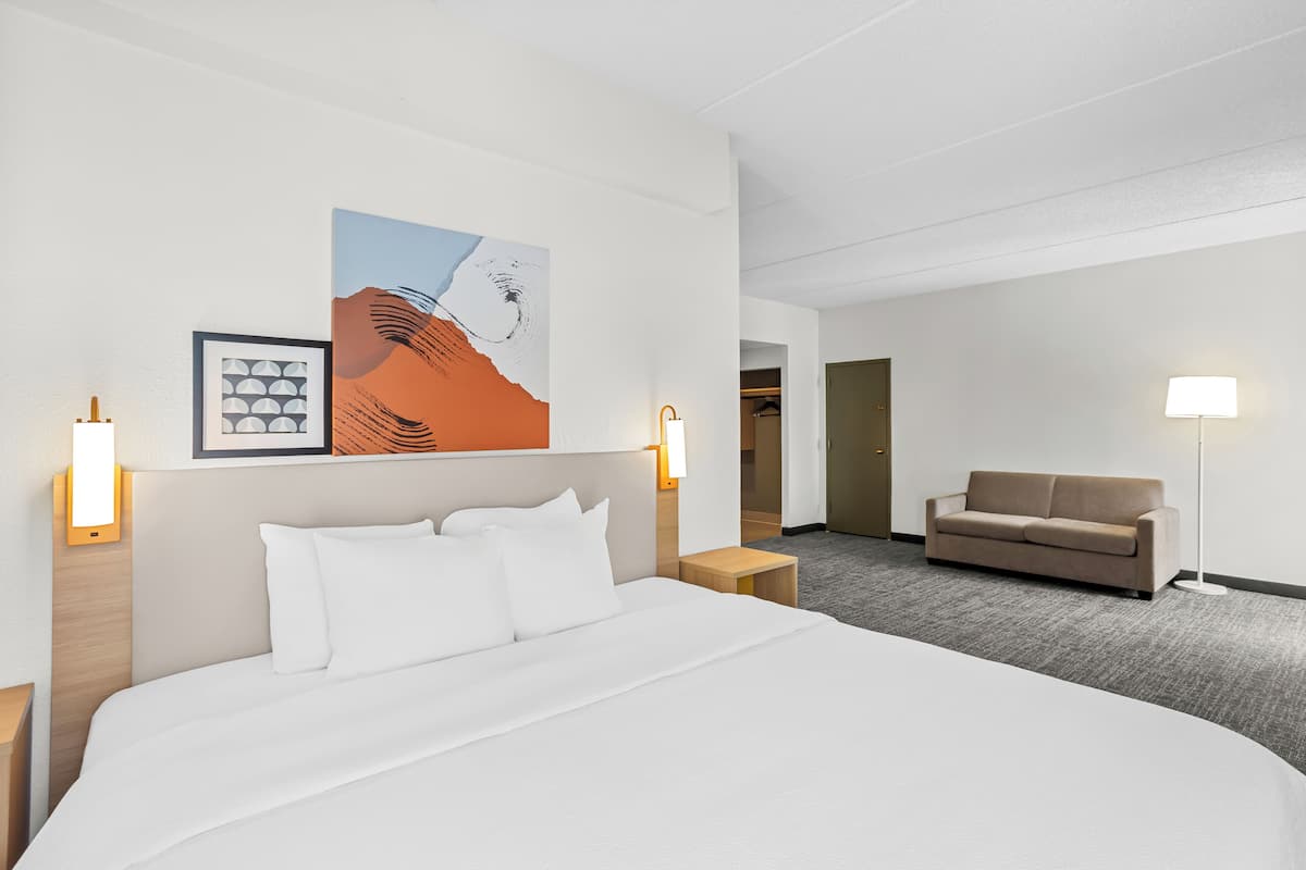 Une chambre d’hôtel avec un grand lit, un canapé et des œuvres d’art accrochées au mur.