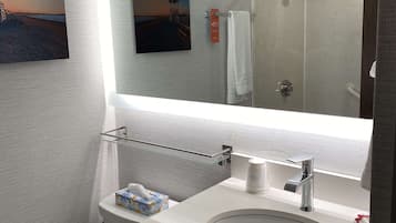 A bathroom with a large mirror, a sink, a towel rack, and a toilet.