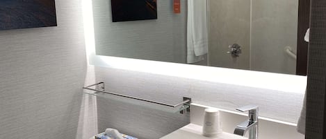 A bathroom with a large mirror, a sink, a towel rack, and a toilet.