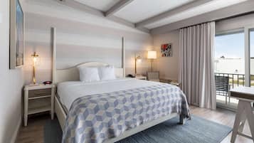 A hotel room with a bed, bedside tables, a desk, and a balcony with curtains.