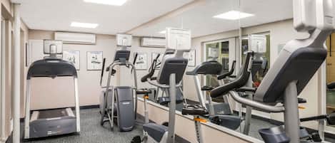 Un gimnasio con cintas de correr, elípticas y una bicicleta estática.