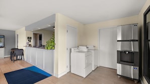 Eine moderne Küche mit eingebauter Waschmaschine und Trockner, einem Kühlschrank und einer Bar mit einer Pflanze.