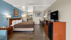 Ein Hotelzimmer mit Bett, Schreibtisch, Fernseher und einem im Hintergrund sichtbaren Badezimmer.