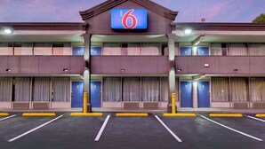 A 6-story motel with a prominent '6' sign, multiple balconies, and a parking lot with marked spaces. - Motel 6 Morgantown, WV (Morgantown)