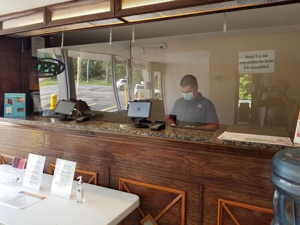 A hotel reception desk with a digital display, a sign indicating room availability, and a notice about unattended items.