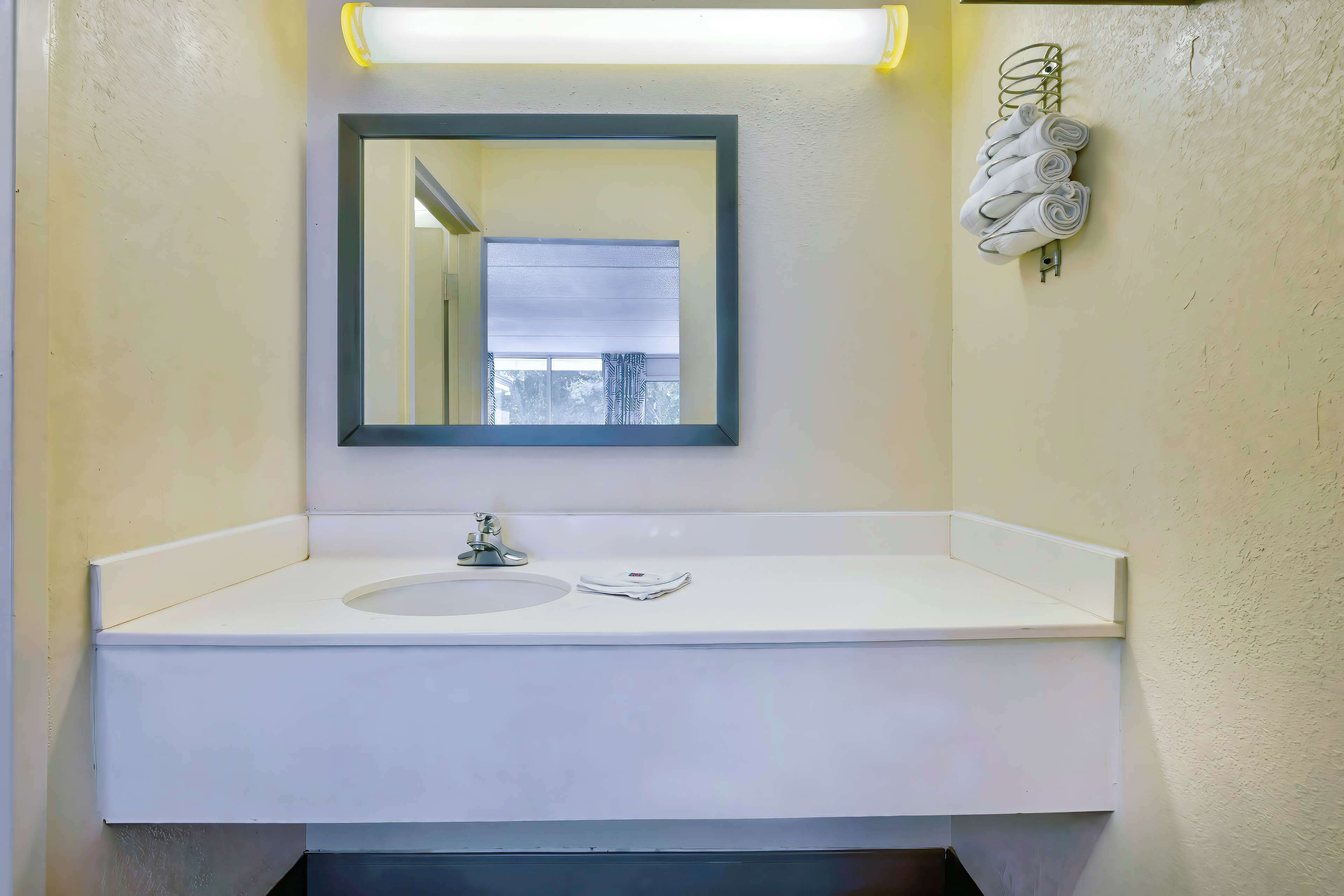 A bathroom with a white sink, a mirror, and a towel rack with towels.