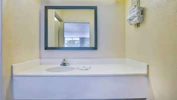 A bathroom with a white sink, a mirror, and a towel rack with towels.