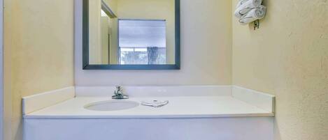 A bathroom with a white sink, a mirror, and a towel rack with towels.