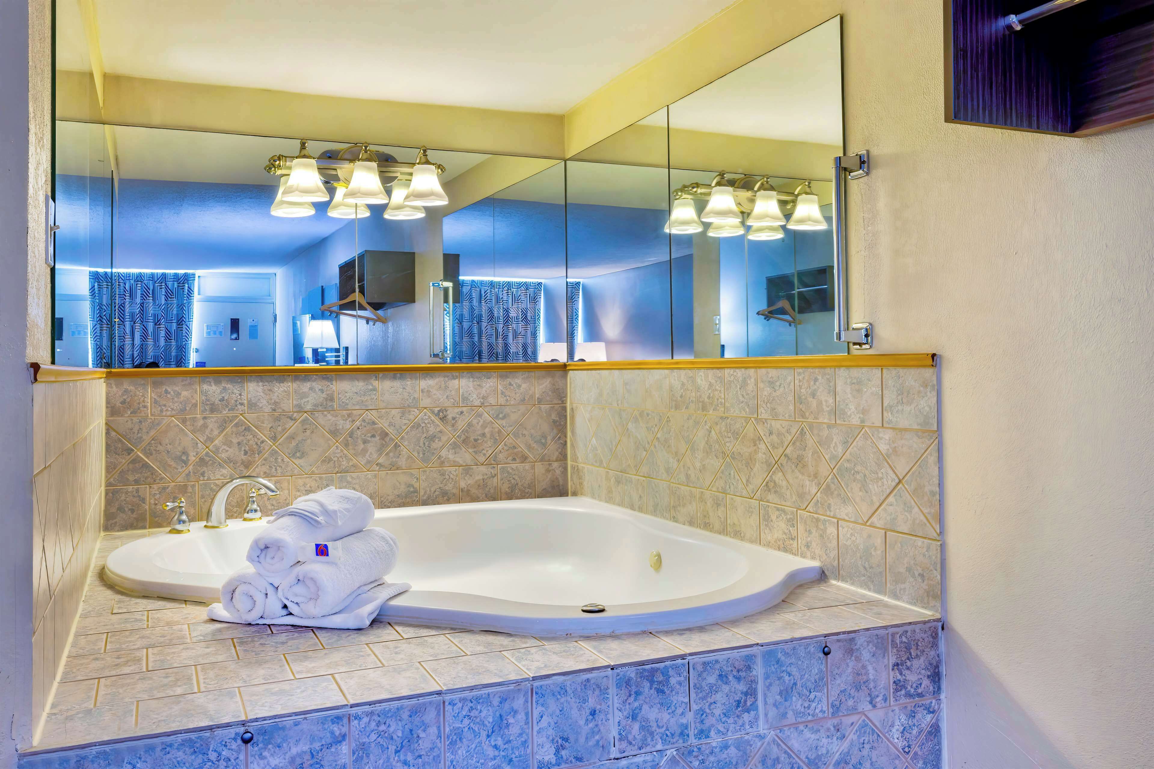 A bathroom with a large mirror, a bathtub, and a sink.