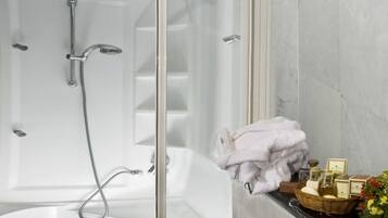 Un bagno moderno con doccia vetrata, una vasca da bagno bianca e una parete in marmo.