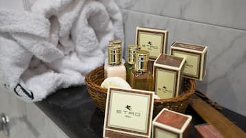 Une salle de bain avec un comptoir en marbre, une serviette blanche et un panier contenant des articles de toilette et une bouteille dont le bouchon est doré.