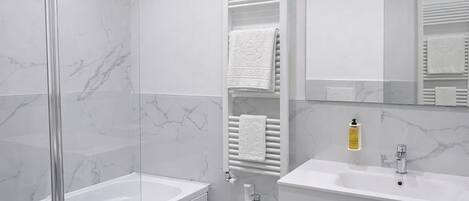 Un baño moderno con ducha de vidrio, un bidé y un tocador con espejo.
