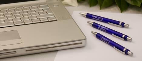 Un ordinateur portable, un microphone et trois stylos sont posés sur une table ornée de fleurs blanches.