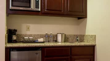 Una cocina compacta con armarios de madera, lavavajillas de acero inoxidable, microondas y cafetera.