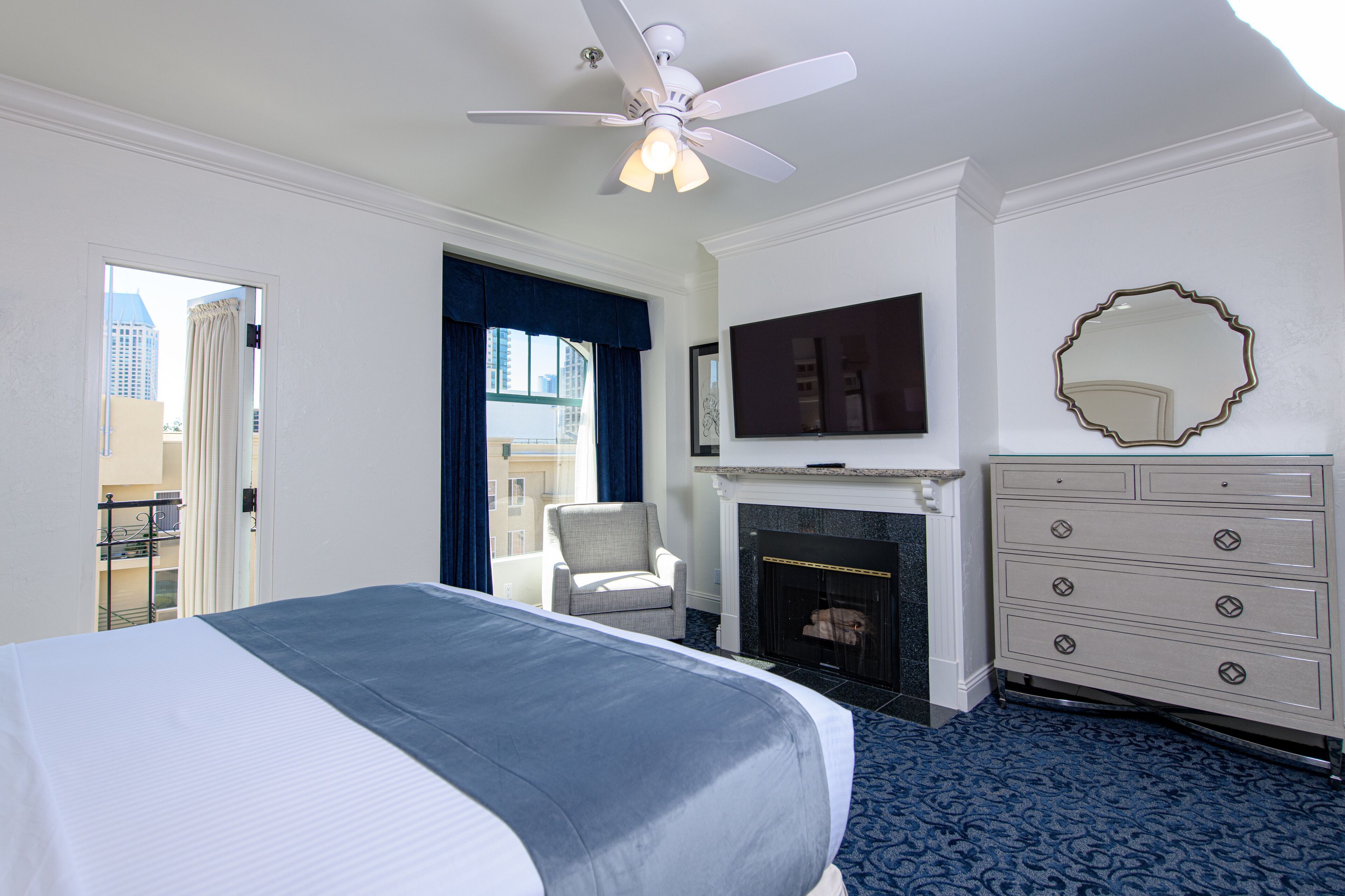A hotel room with a large bed, a fireplace, a television, and a dresser.