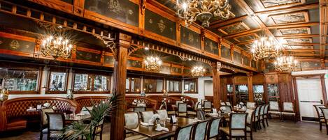 A restaurant with wooden paneling, chandeliers, and a variety of seating options including booths and tables.