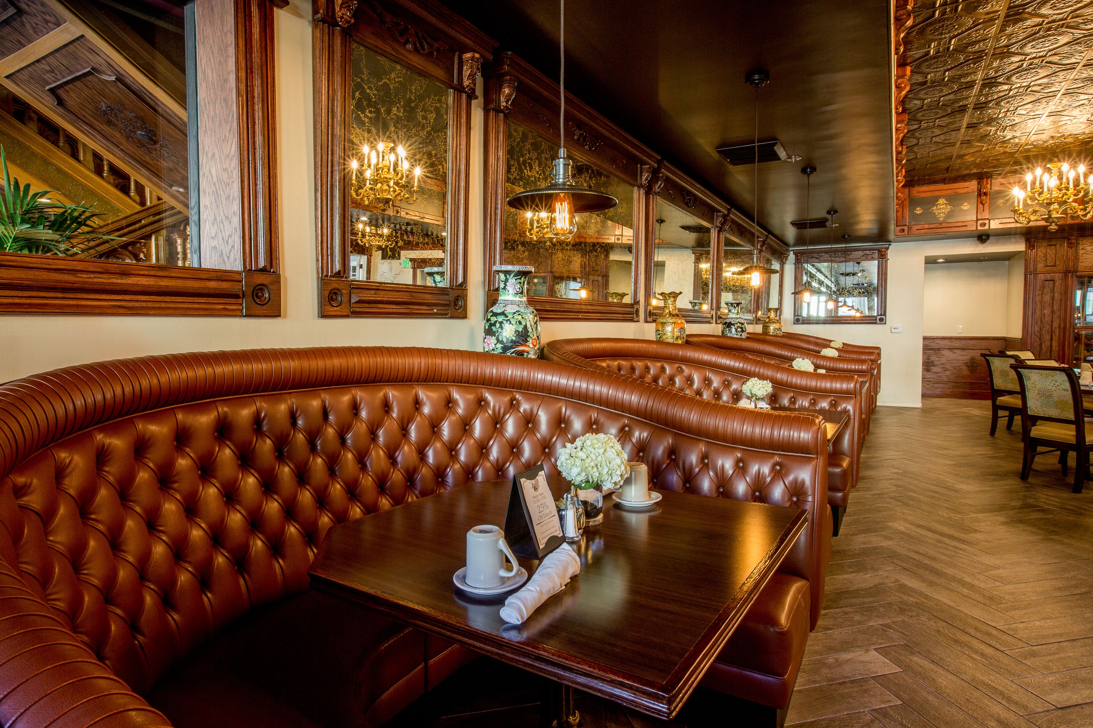 Un restaurante con asientos tipo banca de cuero, mesas de madera y candelabros.