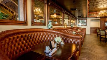 Un restaurante con asientos tipo banca de cuero, mesas de madera y candelabros.