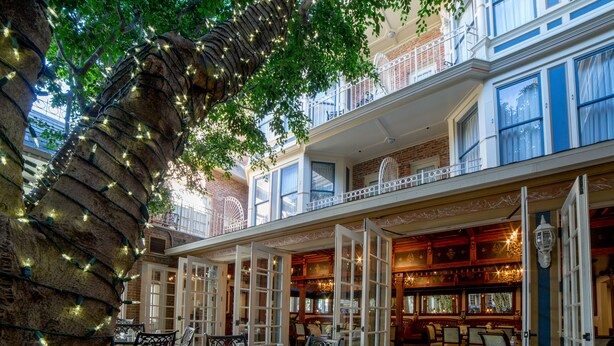 A restaurant with outdoor seating, brick walls, and decorative lighting.