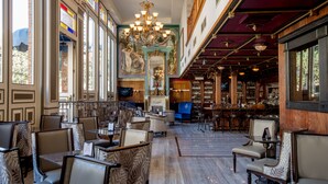A spacious lobby with a bar area, seating arrangements, and a large chandelier.