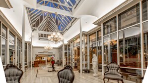A spacious lobby with high ceilings, large windows, and elegant furniture.