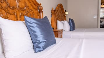 Une chambre d’hôtel avec deux lits, chacun doté de draps blancs et d’oreillers bleus. Les têtes de lit sont en bois et présentent des sculptures complexes.