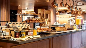 A breakfast buffet with various pastries, bread, and condiments.