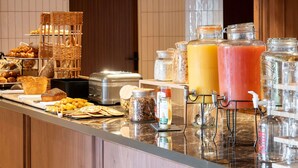 A breakfast buffet with various pastries, bread, and beverages.