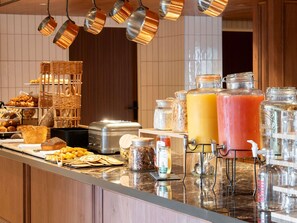 A breakfast buffet with various pastries, bread, and beverages.