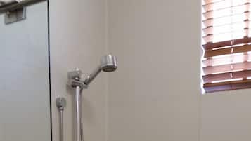 Un espace douche équipé d’un pommeau de douche à main, d’un flexible de douche et d’une barre d’appui.