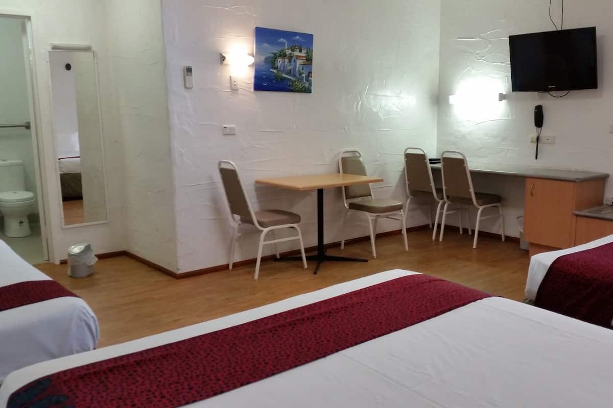 Ein Hotelzimmer mit zwei Betten, einem Schreibtisch und einem Fernseher.
