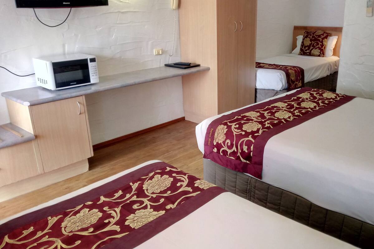 Ein Hotelzimmer mit zwei Betten, einer Mikrowelle, einem kleinen Schreibtisch und einem Telefon.