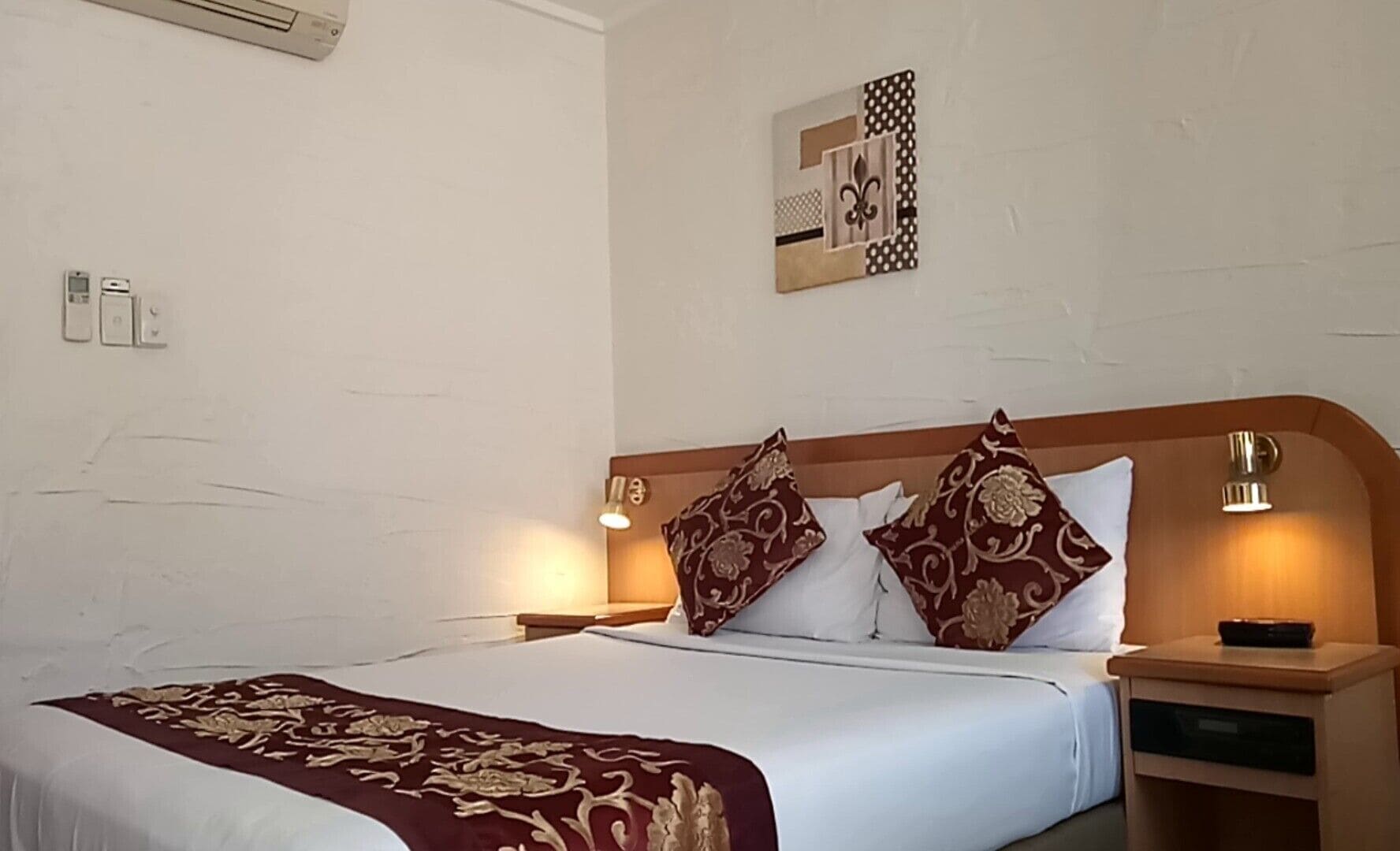 Una habitación de hotel con una cama grande, dos lámparas de noche, una mesita de noche y una obra de arte colgada en la pared.