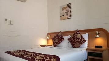 Una habitación de hotel con una cama grande, dos lámparas de noche, una mesita de noche y una obra de arte colgada en la pared.