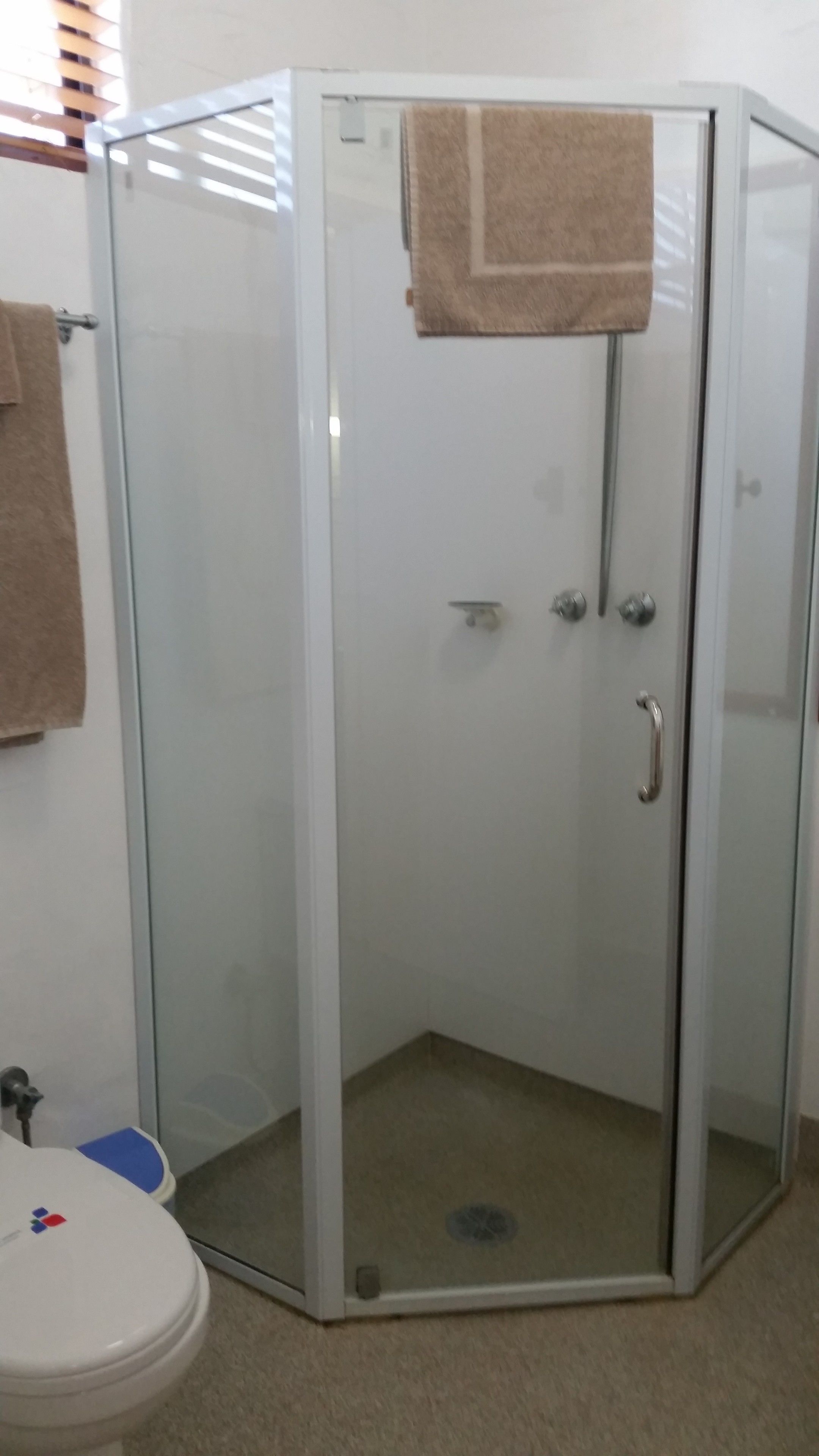 Cabina de ducha con paredes de vidrio y una toalla colgada del pomo de la puerta.