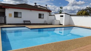 Una piscina con un edificio blanco al fondo.