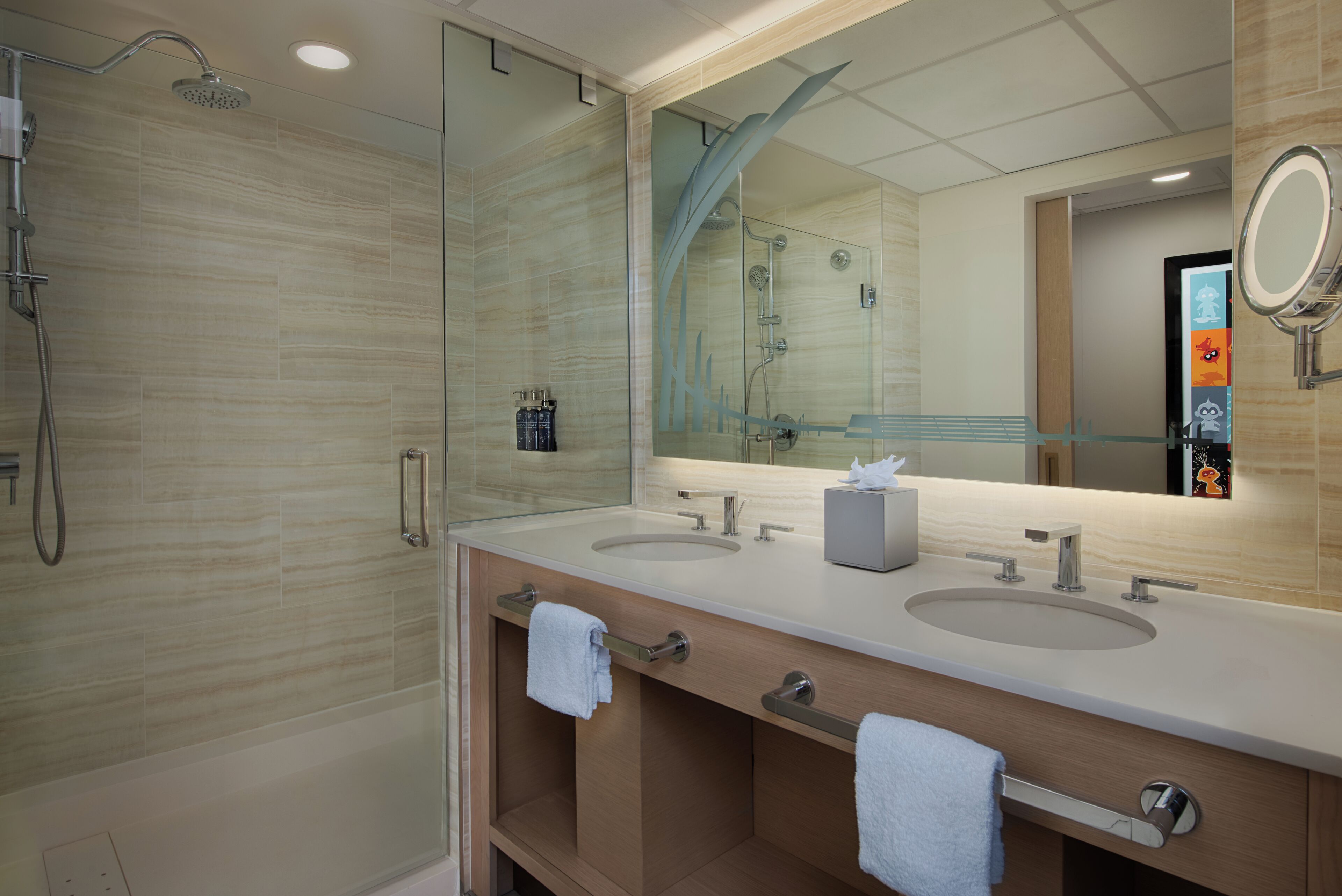 A modern bathroom with two sinks, a glass shower enclosure, and a large mirror.
